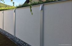 a white fence with grass growing on the top and bottom part, next to a house