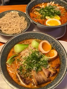 three bowls of food on a table with chopsticks and utensils in them