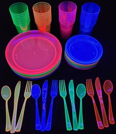 neon colored plastic plates, forks and spoons on a black background