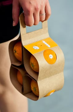 a person holding a paper bag with oranges in it's bottom half and the top half open