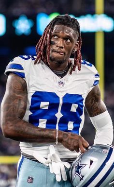 a football player with dreadlocks on his face and holding a ball in one hand