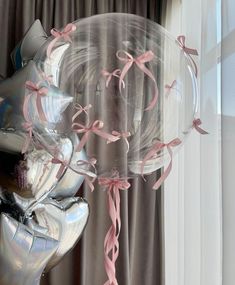 balloons and streamers in the shape of bows are on display near a window with curtains