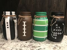 four painted mason jars sitting on top of a counter