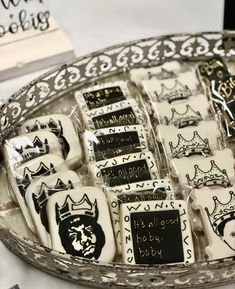 a tray filled with lots of white and black cookies on top of a table next to a sign