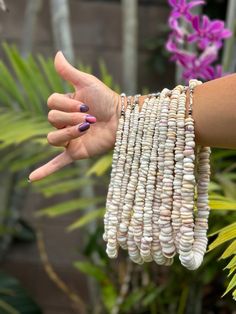 a woman's arm with bracelets made out of shells