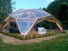 a large glass house sitting on top of a lush green field