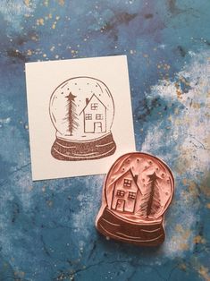 a rubber stamp with a house in a snow globe sitting on top of a piece of paper