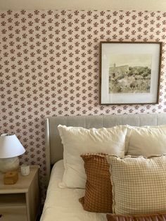 a bed with two pillows on it next to a lamp and pictures above the headboard