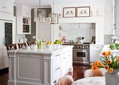 a large kitchen with white cabinets and an island in the center is decorated with orange flowers