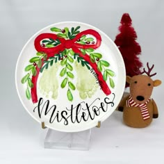 a white plate with a red bow on it next to a christmas tree and a stuffed animal