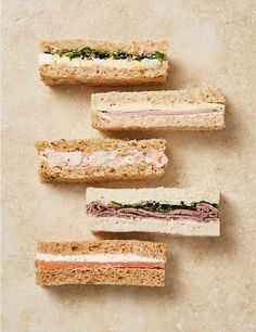 four sandwiches with meat and veggies are arranged in the shape of a rectangle