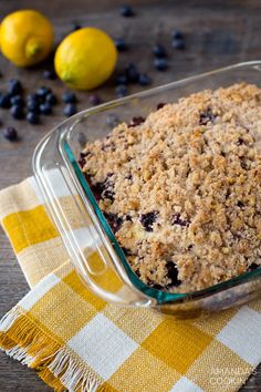 a glass dish filled with blueberries and crumbled oatmeal next to lemons