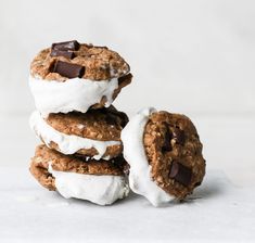 three cookies with white icing and chocolate chips on top are stacked next to each other