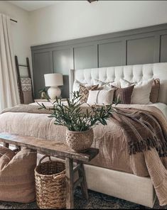 a large bed sitting next to a wooden bench in a bedroom with two lamps on top of it