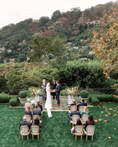 a couple getting married at their wedding ceremony on the lawn in front of a mountain