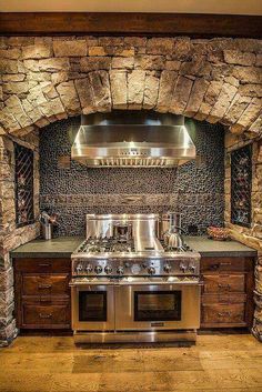 a kitchen with an oven, stove and counter top in stone walled wall above it