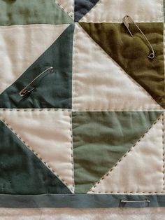 a close up of a patchwork quilt with some pins in the middle on it