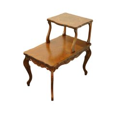 a small wooden table with an intricate design on the top and bottom shelf, sitting against a white background