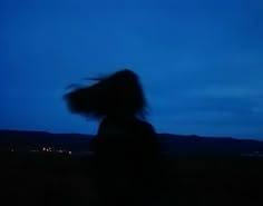 a blurry photo of a person with long hair in the air at night time