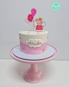 a pink and white cake with pep the pig on top is sitting on a pedestal