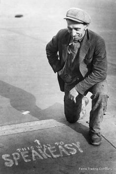 an old black and white photo of a man standing next to a sign that says speak easy