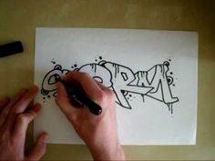 someone is drawing graffiti on a piece of paper with a black marker and it looks like they are doing something