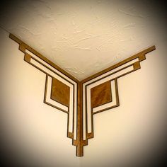 an art deco wall hanging in the corner of a room with white walls and gold trim