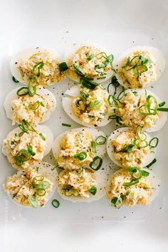 deviled eggs topped with cheese and herbs on a white plate