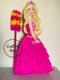 a barbie doll in a pink dress next to a red flower and a yellow stick