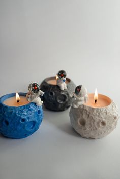 three small candles sitting next to each other on top of a white surface with one candle lit in the middle