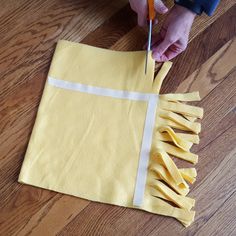 someone is cutting fabric with scissors on the floor next to a piece of yellow cloth