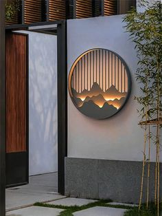 a circular mirror on the side of a building next to a bamboo plant and tree