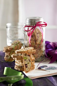 cookies are stacked on top of each other in front of a glass jar with purple ribbon