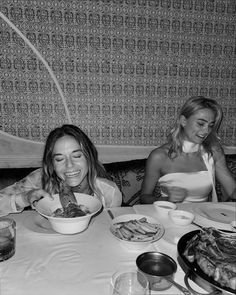 two women sitting at a table with plates of food