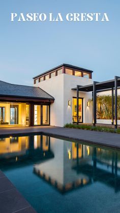 a large swimming pool next to a white house with glass doors and windows on the side