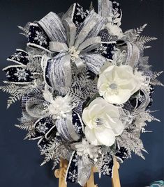 a bouquet of white flowers sitting on top of a wooden easel in front of a blue wall