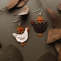 two earrings with flowers and roosters on them