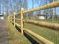 a wooden fence in the grass next to a road