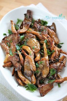 a white bowl filled with chicken wings and garnished with parsley on top