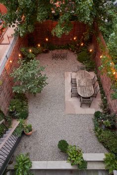 an overhead view of a patio with table and chairs surrounded by greenery, lights and potted plants