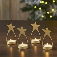 three small candles are placed in front of a christmas tree