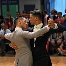 two men in tuxedos are dancing on the dance floor with their arms around each other