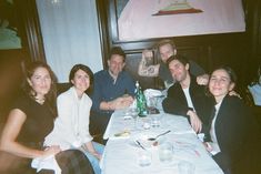 a group of people sitting at a table in front of a painting on the wall