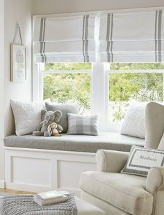 a window seat with pillows and a stuffed animal in front of it, sitting next to a window