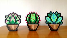 three pixelated cactuses sitting on top of a wooden table next to each other