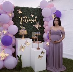 a pregnant woman standing in front of a backdrop with balloons and butterfly decorations on it