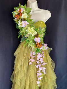 a dress made out of tulle with flowers and butterflies on the front, sitting on a mannequin