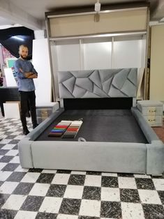 a man standing next to a bed in a room with black and white checkered flooring