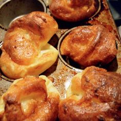 some muffins are sitting on a baking pan with other muffins in it