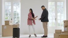 a man and woman standing next to each other in a room with boxes on the floor